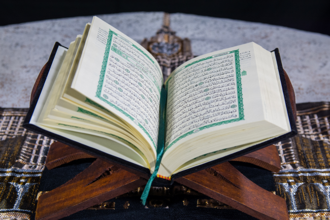 An open Quran resting on a wooden stand, with the recited verses that stopped Umar ibn al-Khattab in his tracks and led him to embrace Islam.